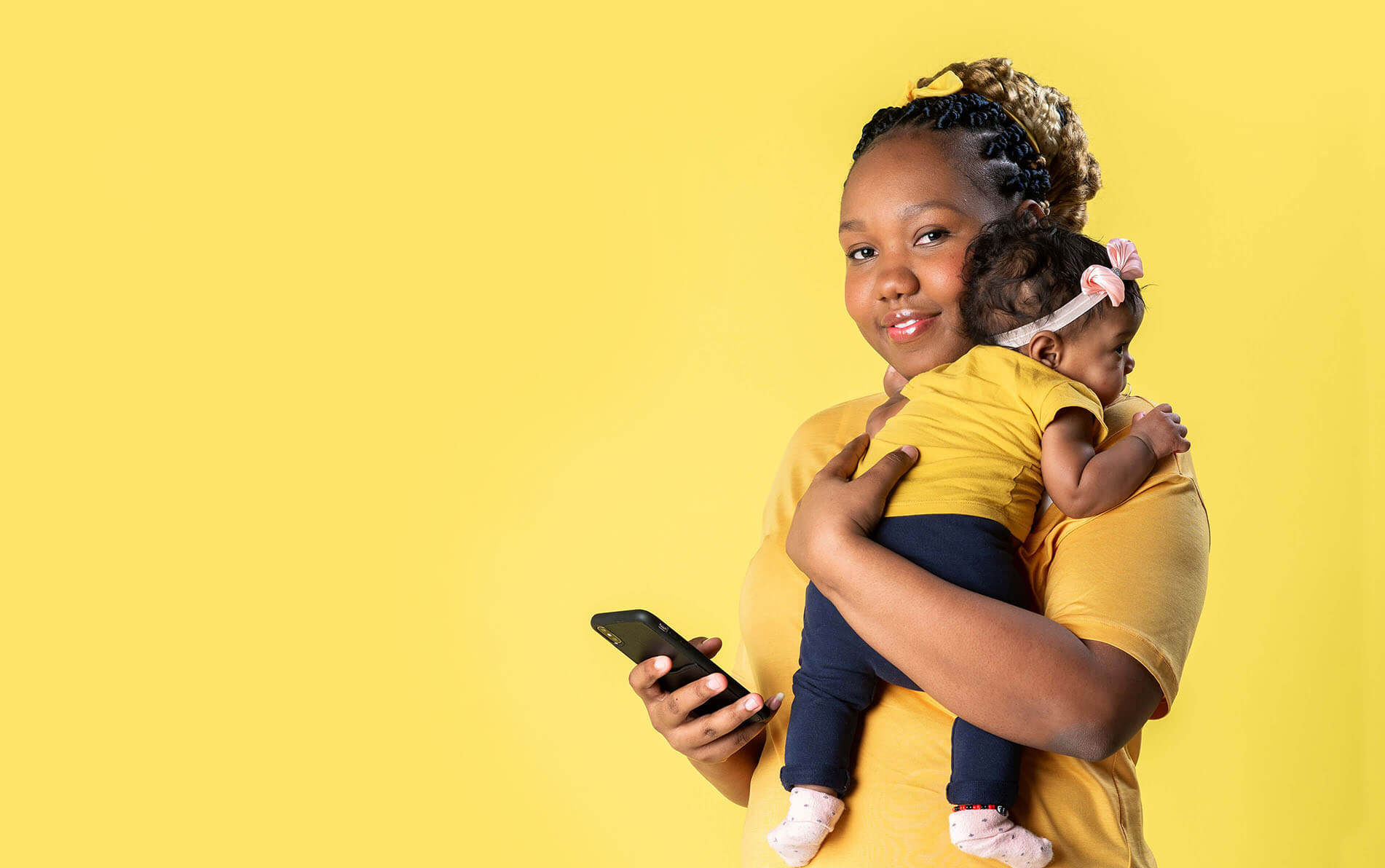Vrouw met baby onder haar arm en een mobiele telefoon in haar hand